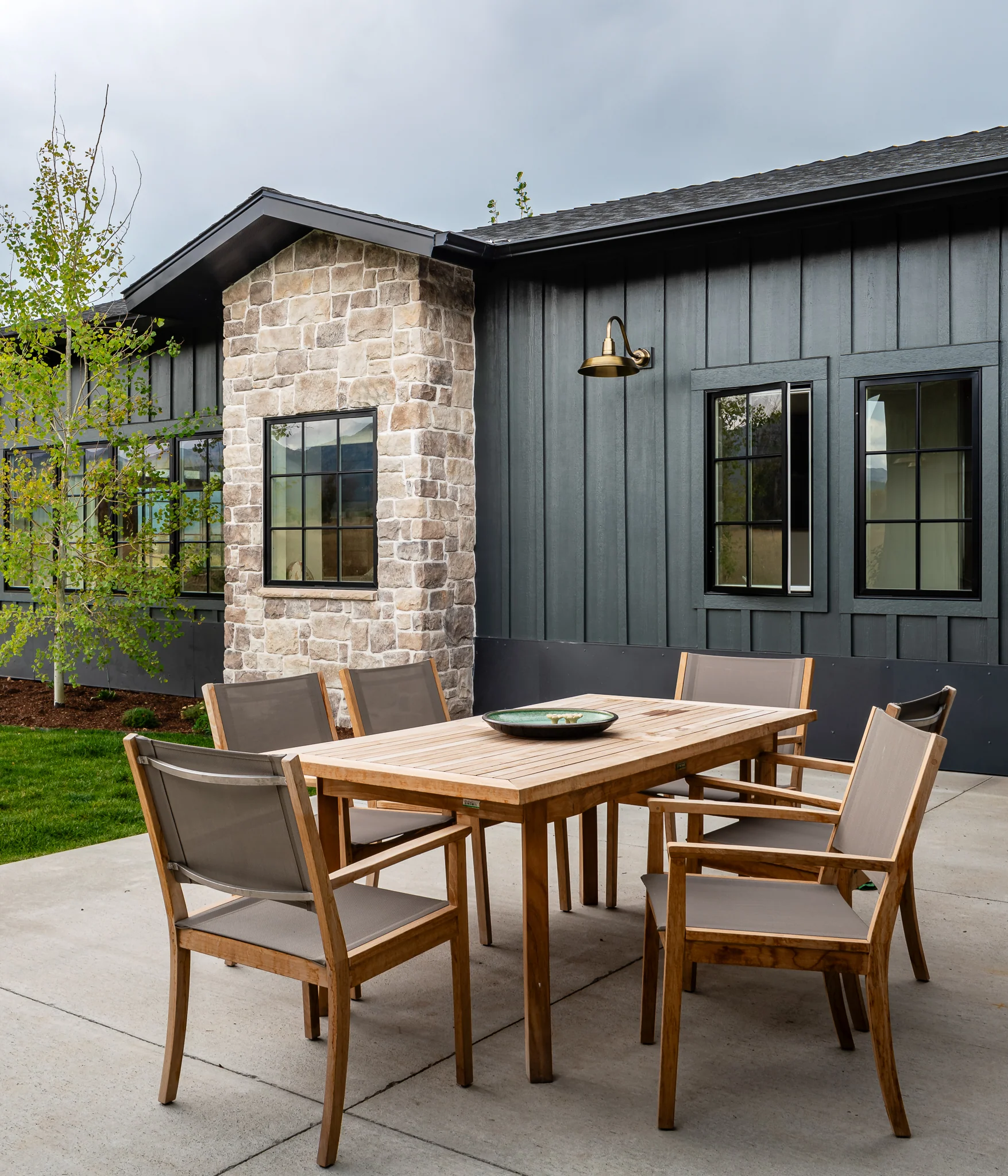 Exterior patio dining table against the stone chimney and dark siding — architectural photography Driggs Idaho, WTG Architects